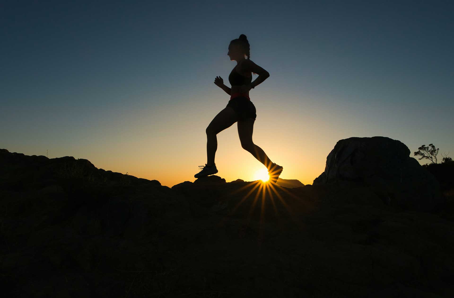 Silhouette of active woman running outdoors at sunset